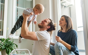 A young couple playing and having fun with their infant child.